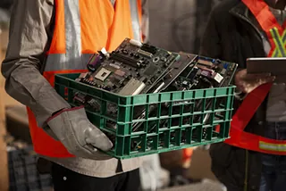 Mitarbeiter trägt Kiste voll Elektroschrott